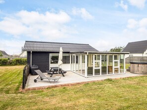 Une maison dotée d’un patio couvert, d’un espace barbecue et d’une pièce fermée par des baies vitrées.