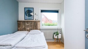A bedroom with a bed, a radiator, a window, and a framed picture on the wall. - 4 Star Holiday Home in Ulfborg (Ulfborg)