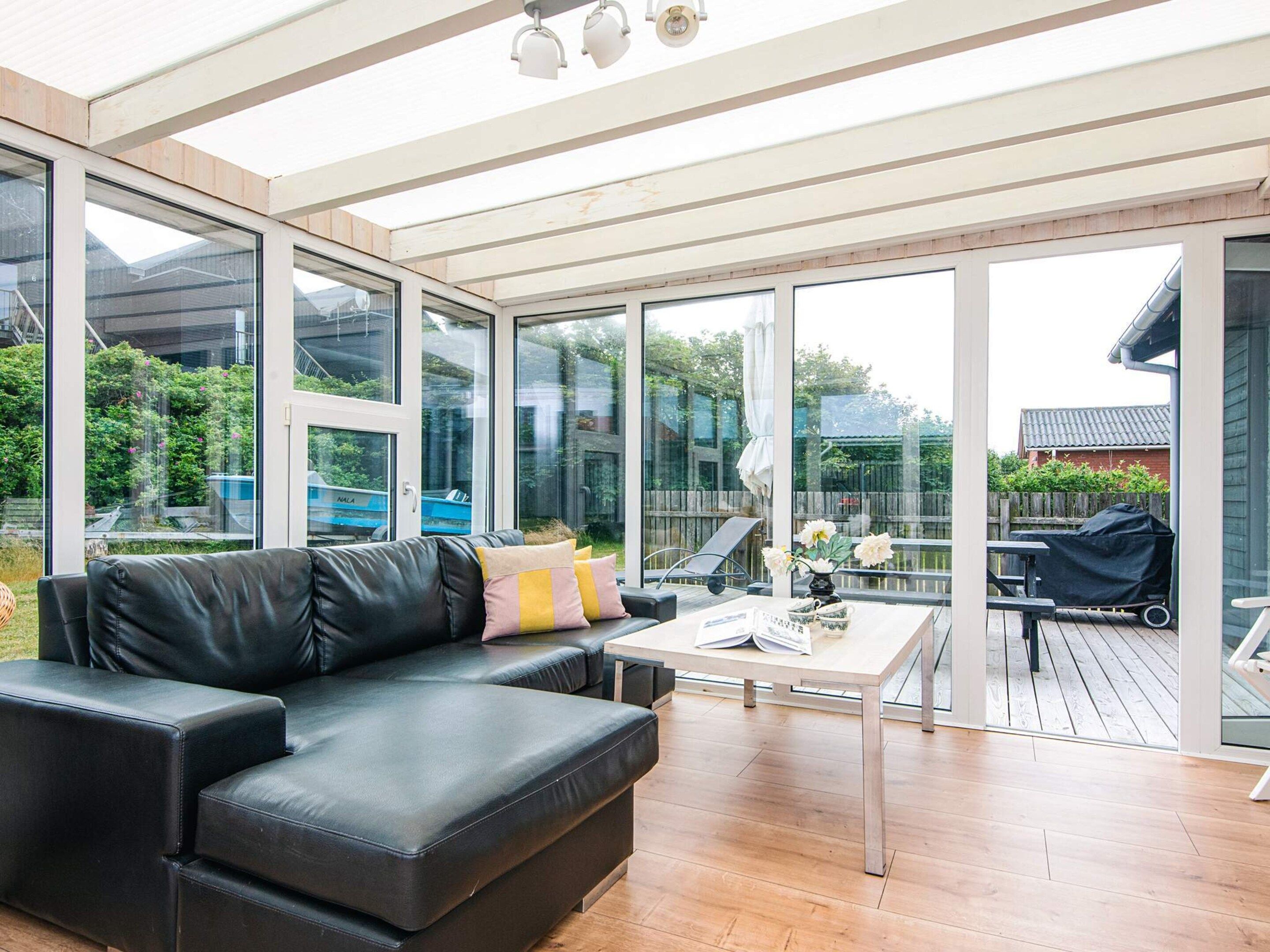 A modern living room with a black leather sofa, a coffee table, and large glass doors leading to an outdoor deck.