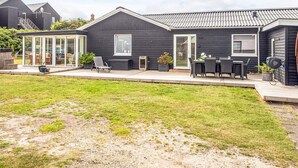 A modern house with a patio, a covered outdoor seating area, and a garden. - 4 Star Holiday Home in Ulfborg (Ulfborg)