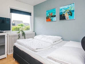 A bedroom with a bed, a TV, and two paintings on the wall. - 4 Star Holiday Home in Ulfborg (Ulfborg)