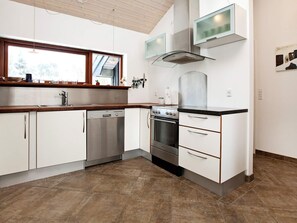 A modern kitchen with white cabinetry, stainless steel appliances, and a window above the sink.