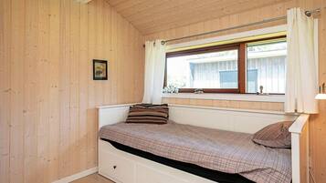 Ein Einzelbett mit Stauraumschubladen, ein Fenster mit Vorhängen und ein Bild an der Wand.