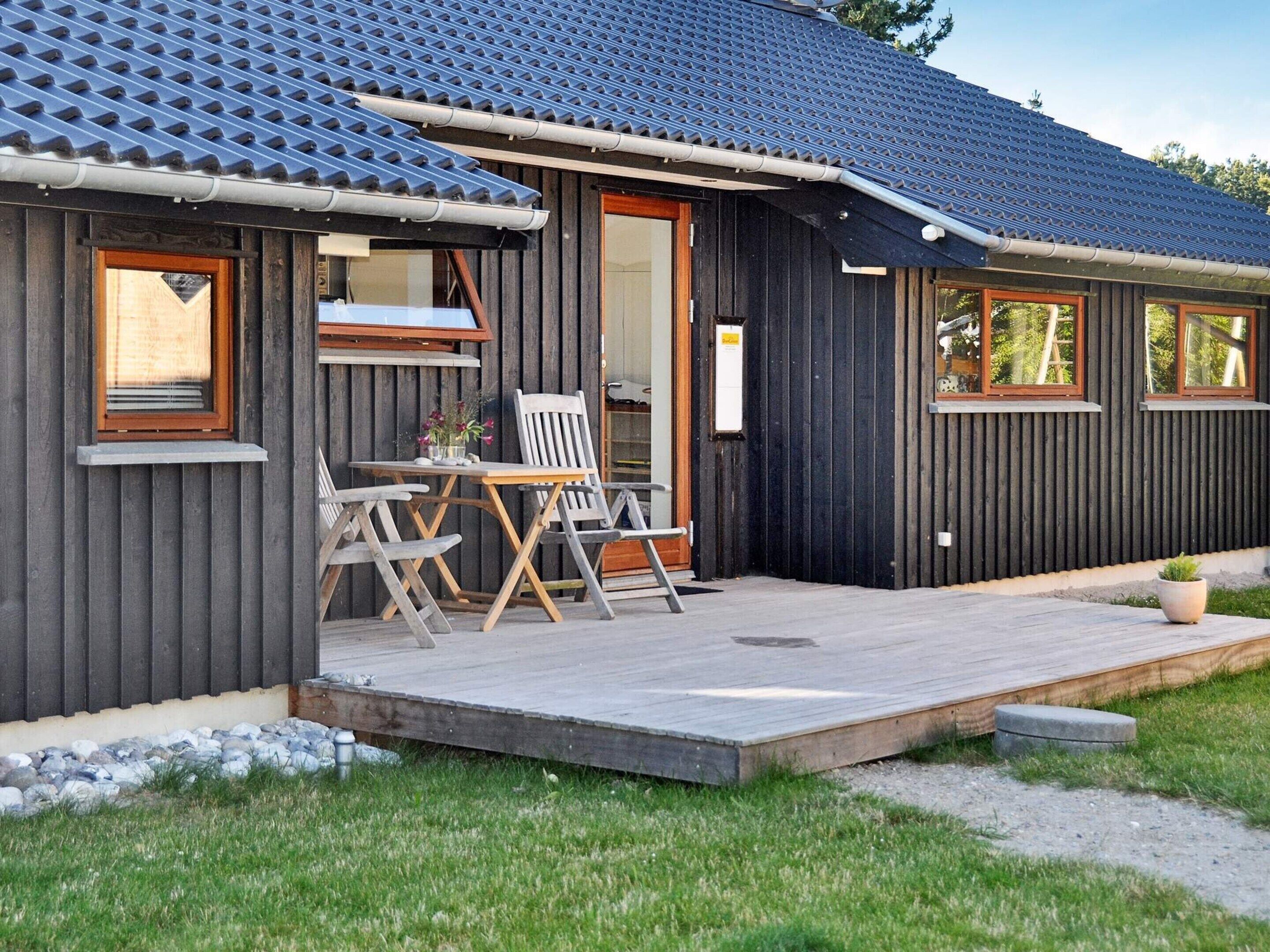 A wooden cabin with a porch, a table, and two chairs.