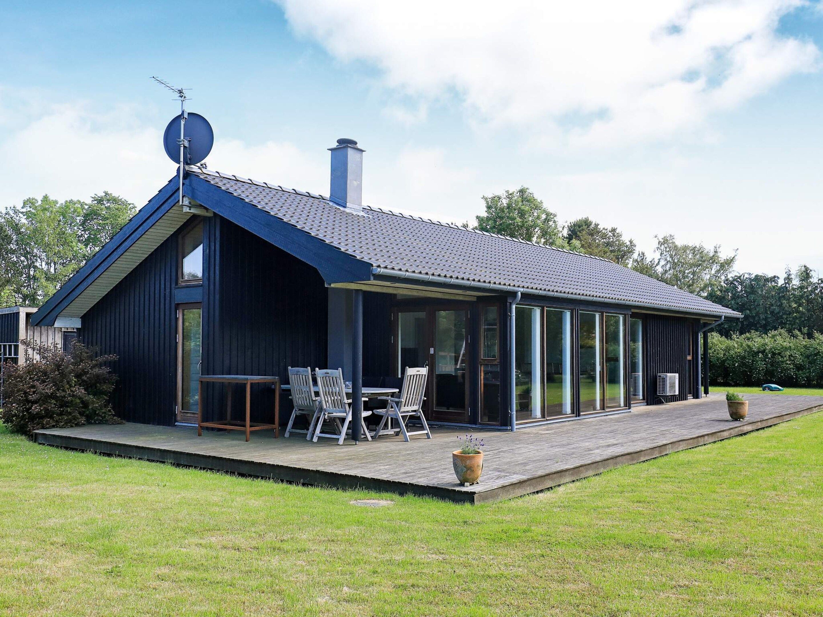 Una casa moderna con un porche techado, ventanas amplias y una antena parabólica.
