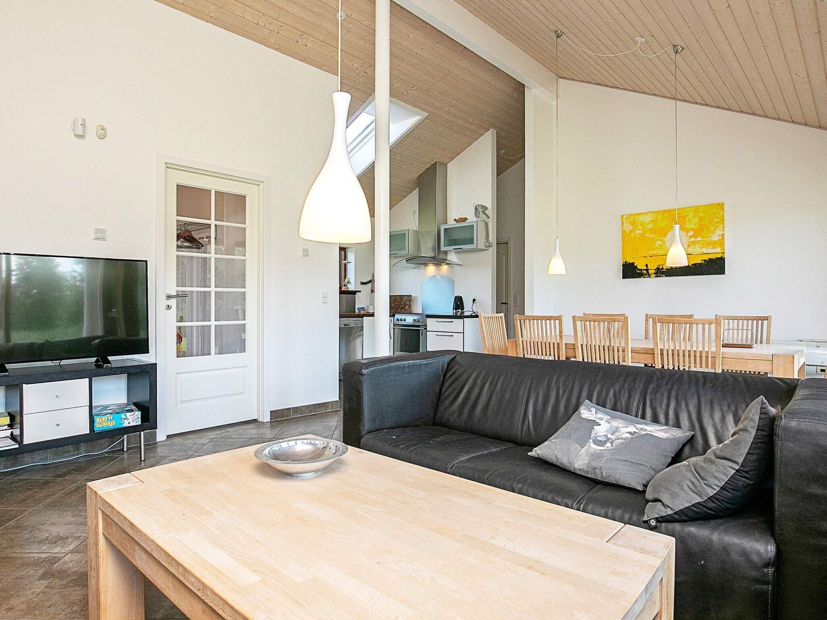 Ein modernes Wohnzimmer mit einer Ledersofa, einem Holztisch und einem Fernseher.