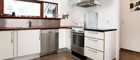 A modern kitchen with white cabinetry, stainless steel appliances, a window, and a built-in oven.