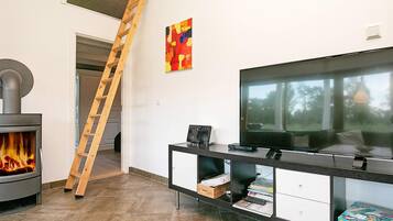 A modern living room with a fireplace, a TV, and a ladder.