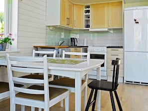 A modern kitchen with white cabinetry, a dining table with chairs, and a refrigerator.