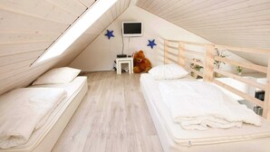A cozy attic bedroom with two beds, a TV, and a teddy bear. - 10 Person Holiday Home in Brovst (Brovst)