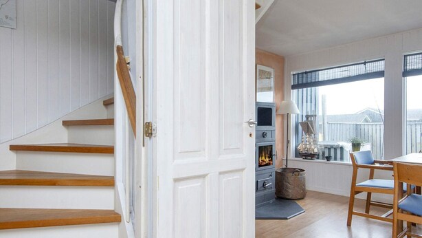 Eine Treppe führt zu einem Essbereich mit Tisch und Stühlen, einem Fenster mit Blick und einem Kamin.