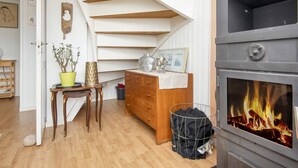 Ein gemütliches Zimmer mit einer Holztreppe, einem Kamin, einer Holzkommode und einem kleinen Tisch mit einer Topfpflanze.