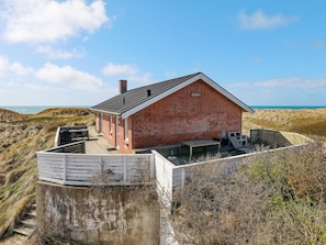 A brick building with a sloped roof, a covered patio area, and a view of the beach. - 4 Star Holiday Home in Lokken (Lokken)