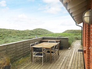 A wooden deck with a table and chairs, overlooking a grassy landscape.