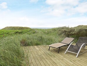 A wooden deck with two lounge chairs facing a coastal landscape. - 4 Star Holiday Home in Lokken (Lokken)