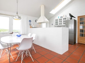 A modern kitchen with a central island, white cabinetry, and a stainless steel refrigerator.