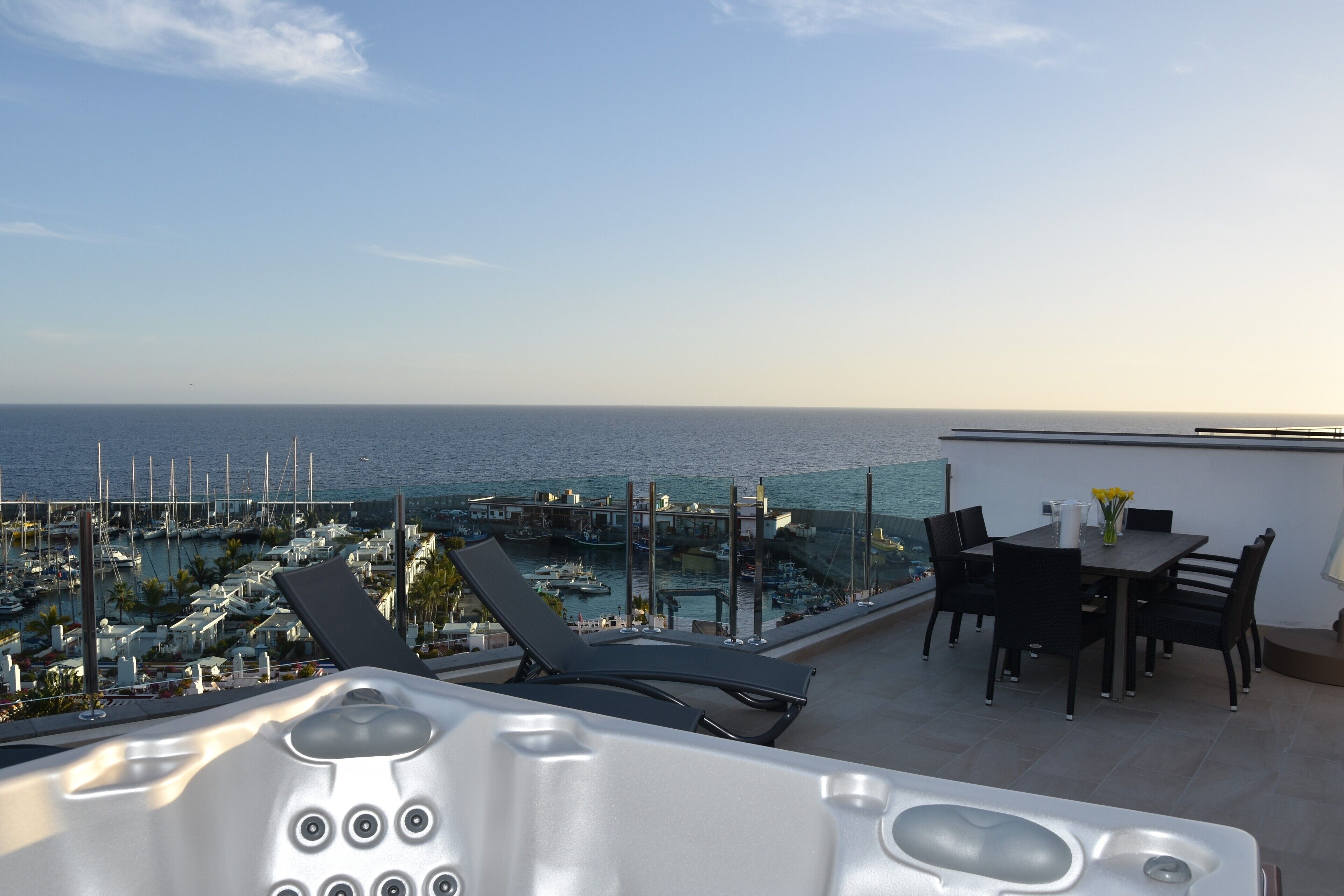 Eine Dachterrasse mit Meerblick, einem Whirlpool und Gartenmöbeln.