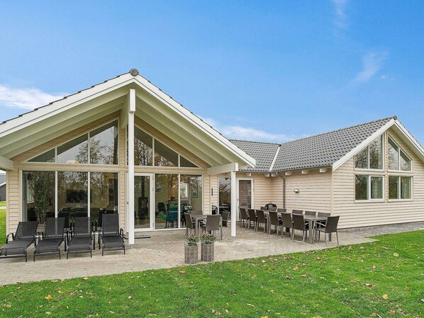 Ein modernes Gebäude mit überdachter Terrasse, großen Fenstern und Außenplätzen.