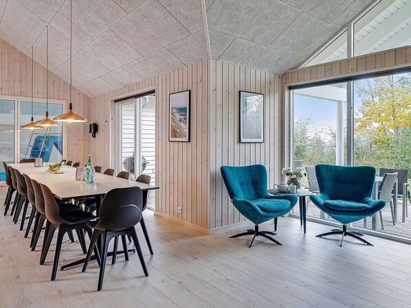 A modern dining area with a long table, black chairs, and teal armchairs. - Holiday Home in Kappeln (Kappeln)