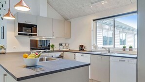 A modern kitchen with a central island, stainless steel appliances, and a large window providing natural light. - Holiday Home in Kappeln (Kappeln)