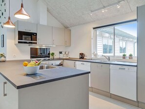 Eine moderne Küche mit einer zentralen Kochinsel, Edelstahlgeräten und einem großen Fenster für natürliches Licht.