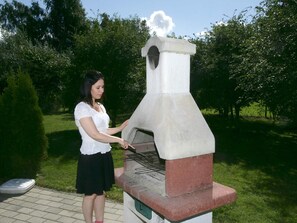 A woman operating a brick-built outdoor oven. - 5 Star Holiday Home in Vaeggerlose (Vaeggerlose)