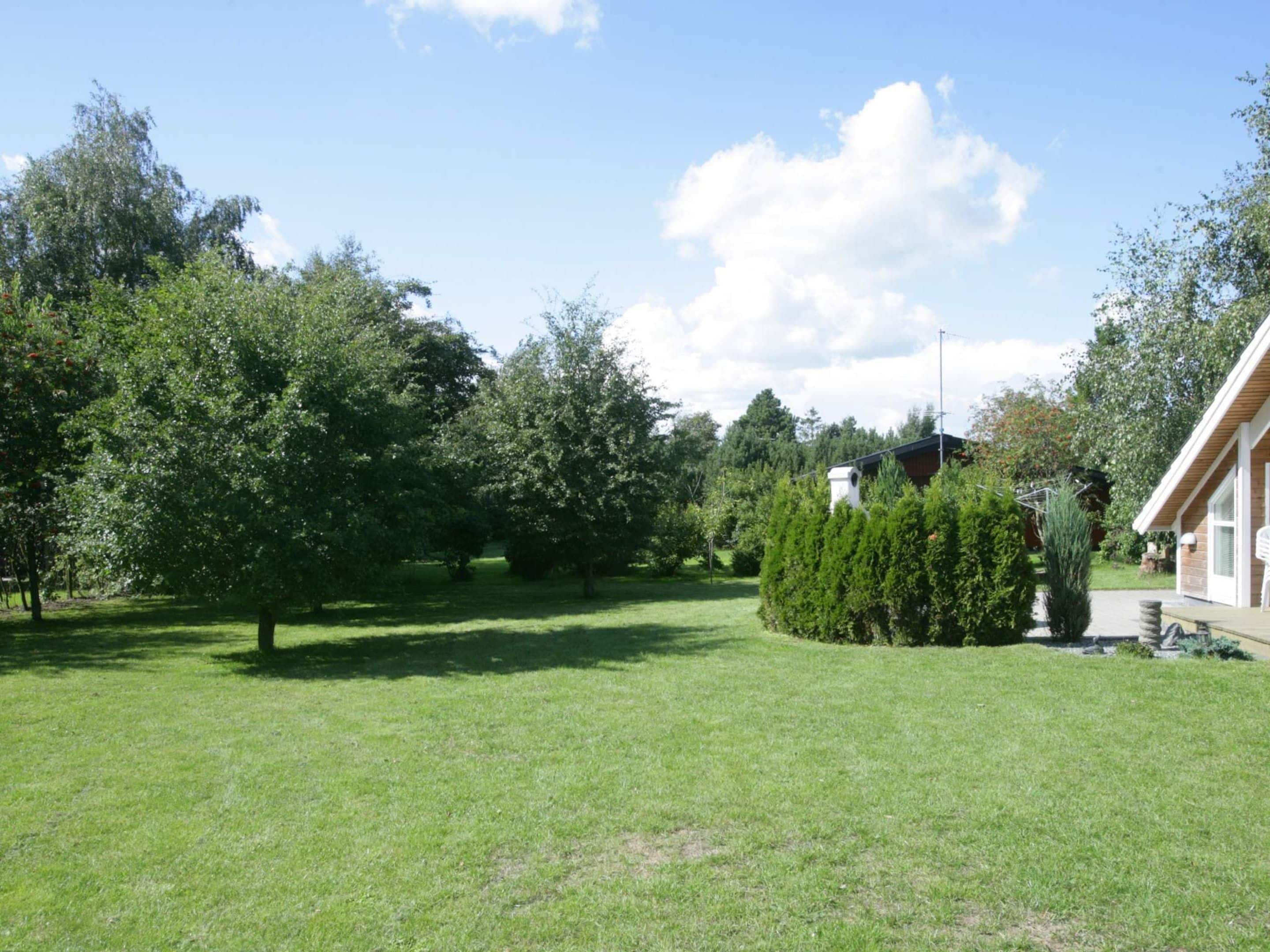 A residential area with a well-maintained lawn, a variety of trees, and a building with a sloped roof.