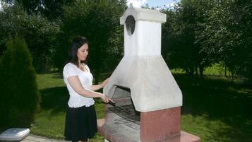 A person operating a brick-built outdoor oven.