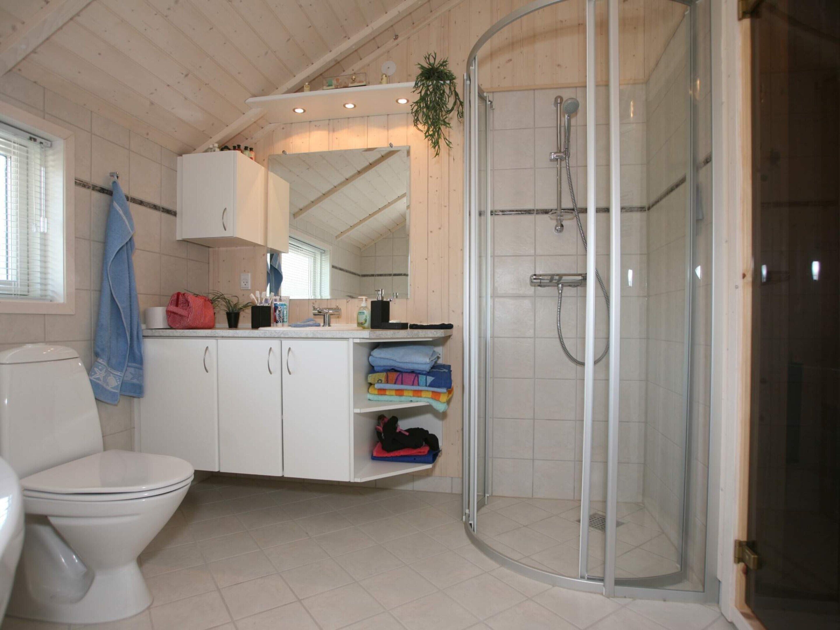 Un baño con inodoro, lavabo, ducha con puerta de cristal y espejo.