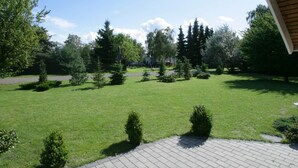 A well-maintained grassy area with a paved walkway, surrounded by trees and shrubs. - 5 Star Holiday Home in Vaeggerlose (Vaeggerlose)