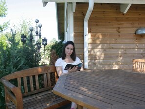 A person sitting at a wooden table outdoors, reading a book. - 5 Star Holiday Home in Vaeggerlose (Vaeggerlose)