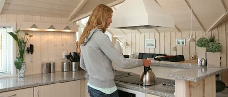 Una mujer en una cocina con paredes de madera, una encimera y un hervidor.