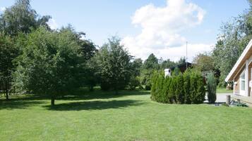 A grassy area with trees and a building with a sloped roof.
