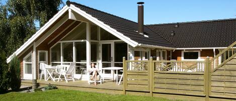 A house with a large porch, a chimney, and a wooden fence.