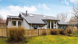 Ett tvåvåningshus med ett sluttande tak, en skorsten och en inhägnad trädgård.
