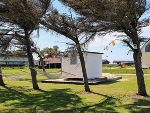 A grassy area with a hammock, a small white building, and trees. - 5 Star Holiday Home in Lokken (Lokken)