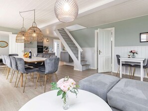 A modern interior with a dining area, staircase, and a living room with a sofa and a table. - 5 Star Holiday Home in Lokken (Lokken)