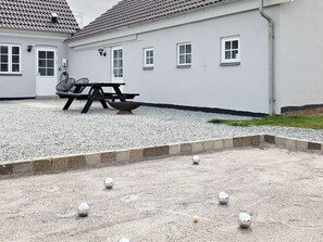 A courtyard with a gravel area, a metal table, and a metal bowl.