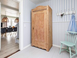 A room with a wooden wardrobe, a light blue chair, and a striped wall.