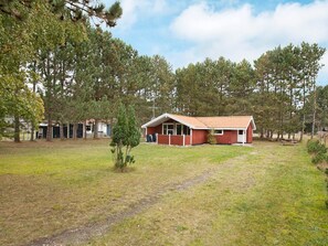 A single-story building with a red exterior and a small front yard. - 6 Person Holiday Home in Rodby (Rodby)