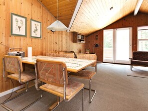 A wooden-paneled room with a dining table, chairs, a radio, framed botanical illustrations, and a bench. - 6 Person Holiday Home in Rodby (Rodby)