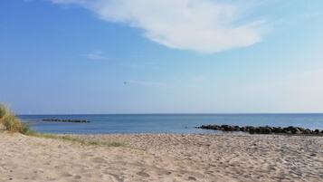A sandy beach with a clear sky and calm sea.
