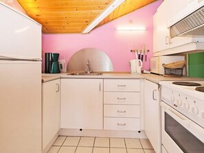 A kitchen with white cabinets, a sink, a stove, and a microwave. - 6 Person Holiday Home in Rodby (Rodby)