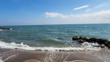 Ein Strand mit Wellen, blauem Himmel und einer felsigen Küste.