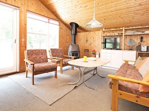 A cozy cabin interior with a sofa, chairs, a table, a fireplace, and a television. - 6 Person Holiday Home in Rodby (Rodby)