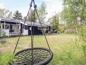 Ein Haus mit Veranda, einer Schaukel und einem Rasen.