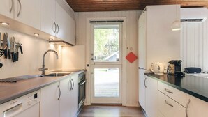 Eine Küche mit weißen Schränken, einem Bosch Geschirrspüler, einer Spüle und einem Fenster.