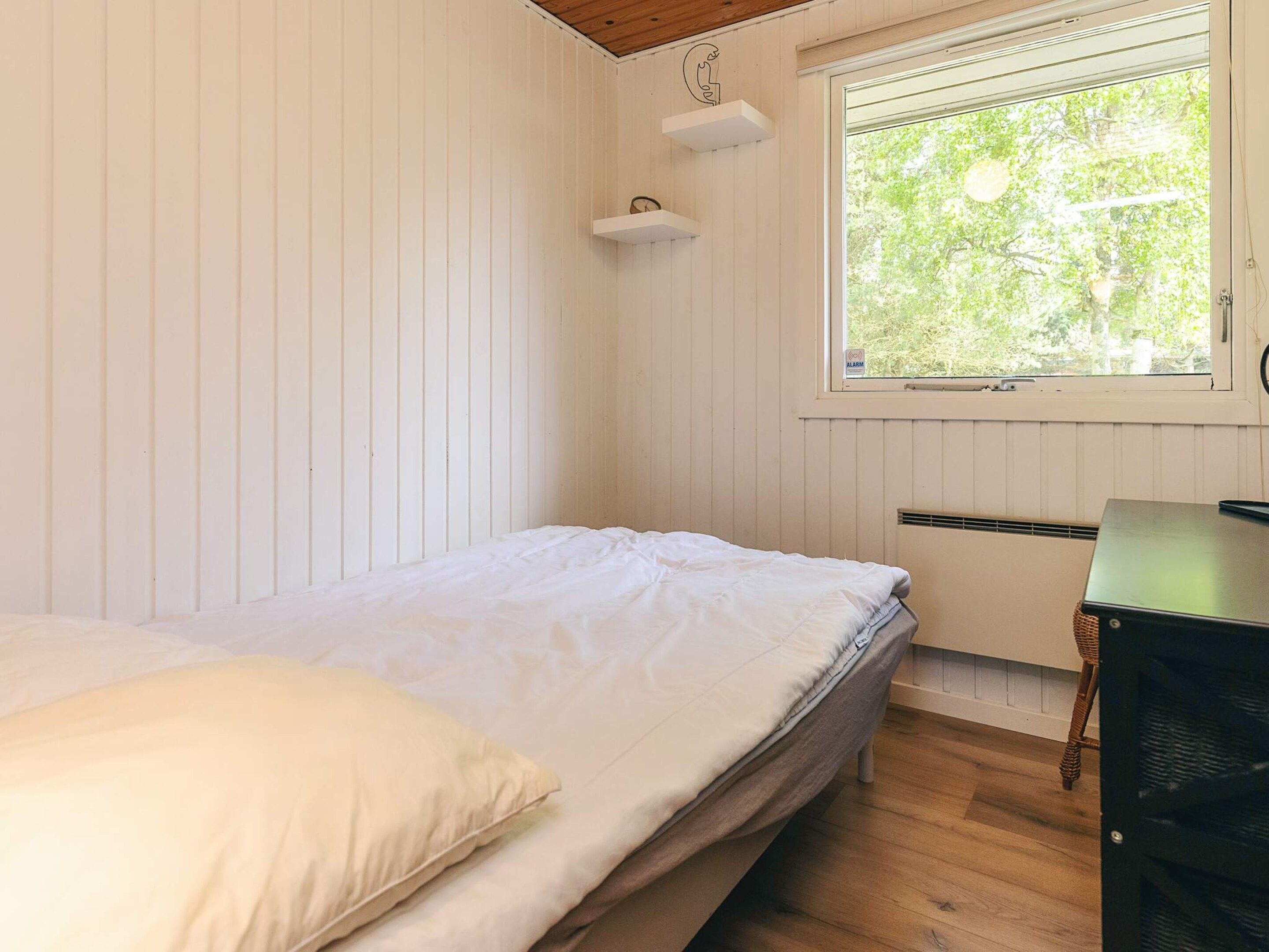 Een kamer met een bed, een raam, een radiator en een bureau.