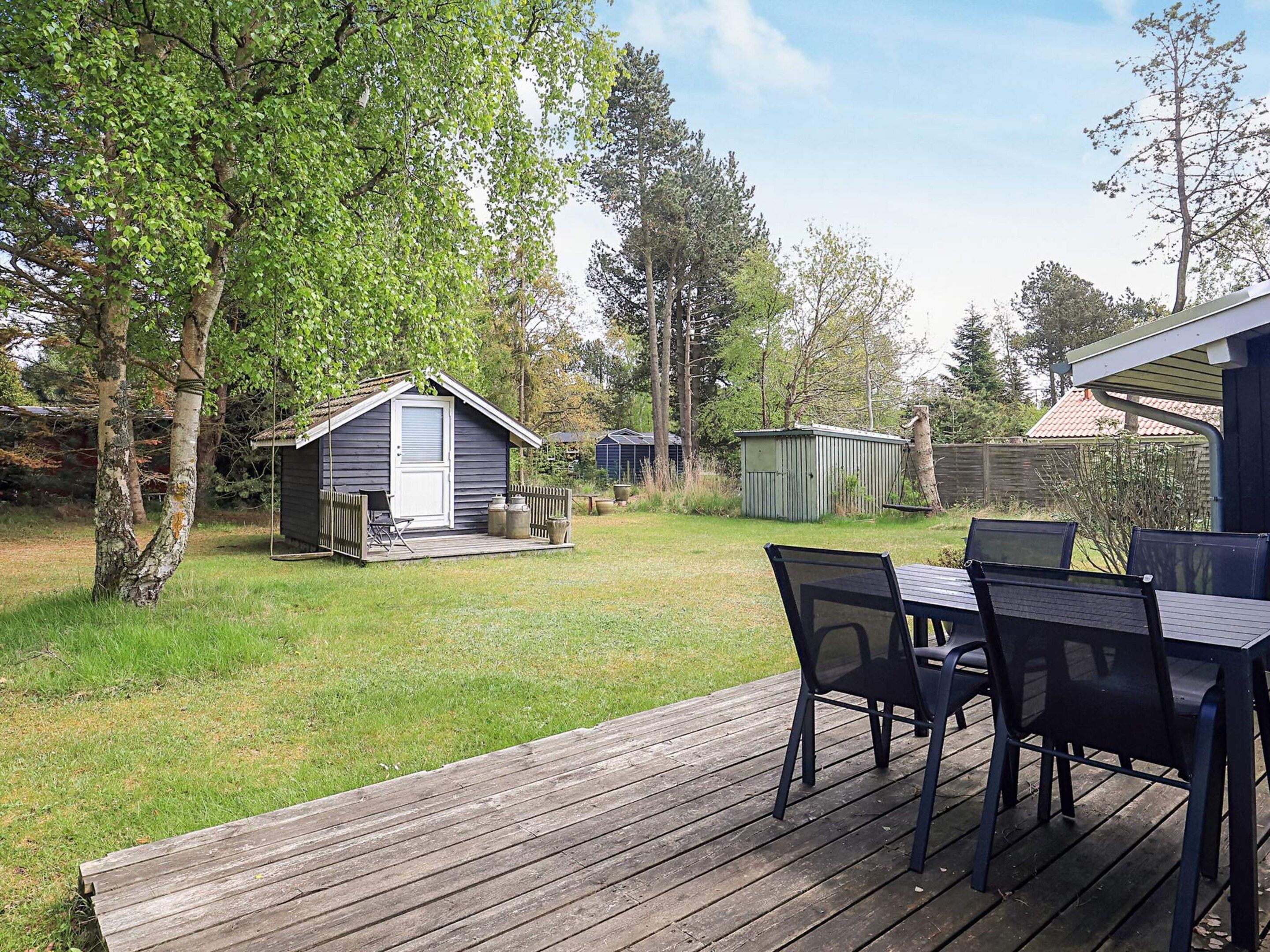 A deck with outdoor furniture, a small shed, and a tree.
