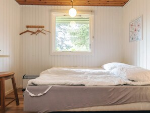 A bedroom with a bed, a window, a hanging light fixture, and a wall-mounted picture.